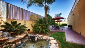 einen Garten mit einem Teich mit einem Tisch und einem Sonnenschirm in der Unterkunft Best Western Burbank Airport Inn in Los Angeles