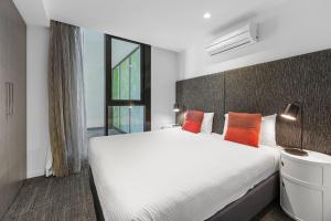 a bedroom with a large white bed with orange pillows at MainStay Suites Abbotsford in Melbourne +66 photos