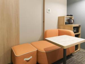 a waiting room with an orange chair and a table at Comfort Hotel ERA Sapporo North in Sapporo