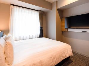 a bedroom with a large bed and a window at Comfort Hotel ERA Sapporo North in Sapporo