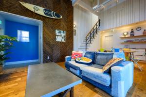 a living room with a blue couch and a table at Aoshima Surfers House in Miyazaki