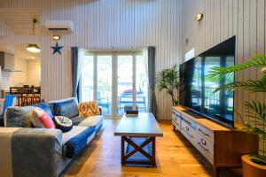 a living room with a blue couch and a tv at Aoshima Surfers House in Miyazaki +25 photos