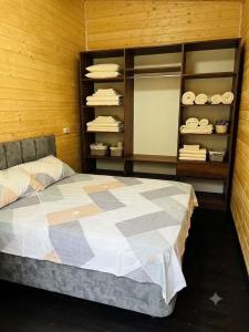 a bedroom with a bed and a shelf with towels at Shekvetili Cottage Nene in Shekhvetili