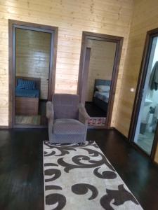 a living room with a chair and a rug at Shekvetili Cottage Nene in Shekhvetili