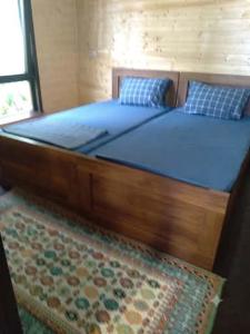a large bed with blue sheets and a rug at Shekvetili Cottage Nene in Shekhvetili