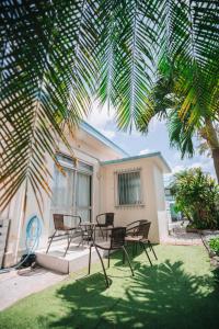 a patio with a table and chairs under a palm tree at Cottage ke'oke'o in Yomitan