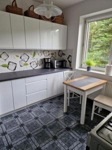 a kitchen with white cabinets and a table at Przestronny, komfortowy dom in Swornegacie