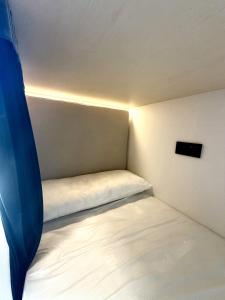 a small bed in a small room with a light at Albergue -Hostel ManuelaINN in El Burgo de Osma
