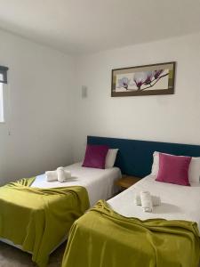 two beds in a room with green and pink sheets at Vila das Pétalas in Portimão