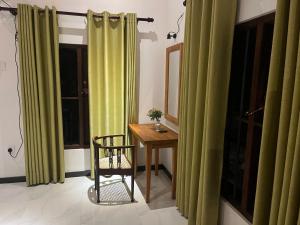 a room with green curtains and a table and a chair at The villa Evans in Pitiduwa