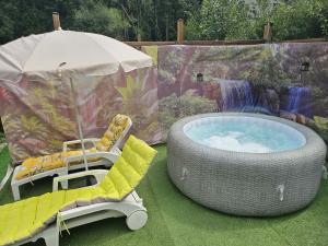 a hot tub and a chair and an umbrella at L'Échappée Verte in Betting-lès-Saint-Avold