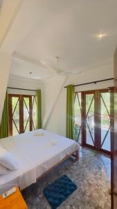 a bedroom with a large white bed with green curtains at Thesrilankaman village in Unawatuna