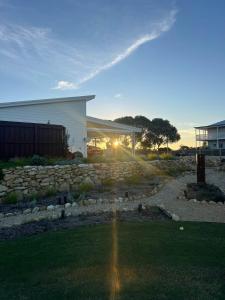 a house with a stone wall in front of a yard at Studio Jean - Dog-Friendly in Bremer Bay