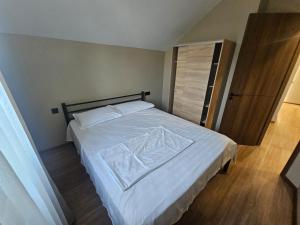 a bedroom with a bed with white sheets and a closet at George House in Batumi
