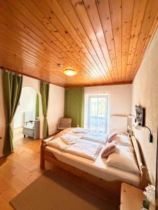 a large bed in a room with a wooden ceiling at Waldhotel Bad Jungbrunn in Tristach