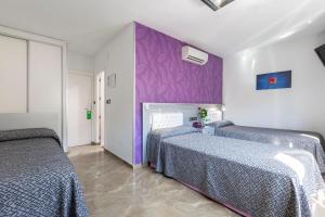a bedroom with two beds and a purple wall at Hotel Molinos in Granada