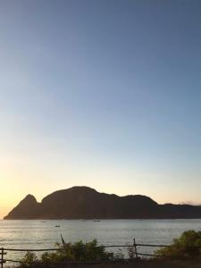 a sunset over a body of water with a mountain at Anorawi Supersuck Surf Accommodation in Maluk