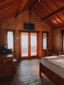 a room with a bed and windows and a tv at Anorawi Supersuck Surf Accommodation in Maluk