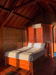 a bedroom with a bed in a wooden room at Anorawi Supersuck Surf Accommodation in Maluk