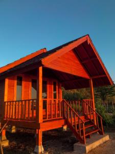 a small wooden house with a large roof at Anorawi Supersuck Surf Accommodation in Maluk