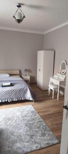 a white bedroom with a bed and a desk at Agroturystyka Kryjówka Nad Stawem in Kodeń