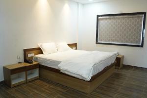 a bedroom with a bed with a nightstand and a window at Hindustan Hotels in Warangal