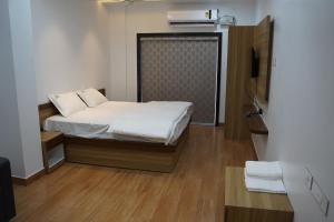 a small bedroom with a bed with white sheets at Hindustan Hotels in Warangal
