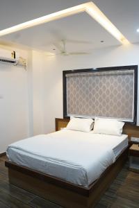 a bedroom with a white bed with two pillows at Hindustan Hotels in Warangal