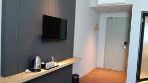 a room with a flat screen tv on a wall at Roxy Hotel Selangau in Rumah Kudan