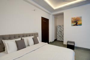 a white bedroom with a large white bed and a door at Amara Inn by Sandane Homes Near Expo mart and Pari Chowk in Greater Noida