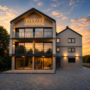 a large building with a sunset in the background at Olimp Apartamenty in Konin