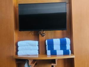 Ein Flachbildfernseher auf einem Regal mit Handtüchern. in der Unterkunft Suites Sol y Luna in Cancún
