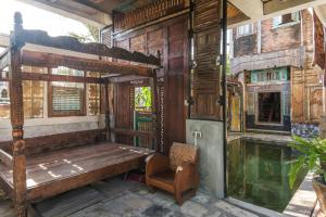 a porch with a wooden bed and a chair at TwoSpaces Living at Bunga Desa, Jimbaran in Jimbaran
