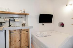 a bathroom with a bed and a sink and a tv at Bougainvillea in Andros