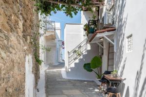 an alley with white buildings and a table and chairs at Bougainvillea in Andros