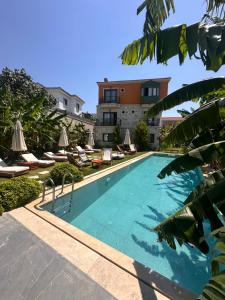 a swimming pool with lounge chairs and a building at Elia Hotel Alaçatı in Çeşme