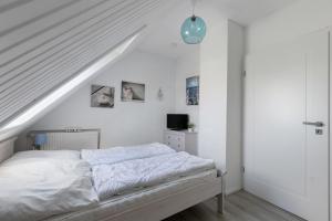 a white bedroom with a bed and a staircase at Fewo Küstkieker in Böhl