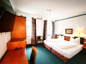 a hotel room with two beds and a desk at Hotel Herzogenrath in Herzogenrath