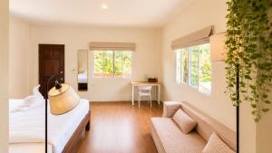 a bedroom with a bed and a couch and two windows at Zen Village in Ko Phangan