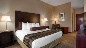 a hotel room with a large bed and a chair at Best Western Plus O'hare International South Hotel in Franklin Park