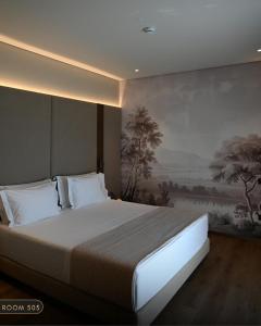 a bedroom with a large bed with a painting on the wall at Elmares Hotel in Himare