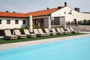 a pool with chaise lounge chairs and umbrellas at Andrássy Kúria & Spa in Tarcal
