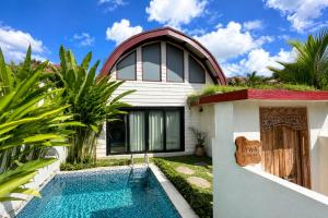 a villa with a swimming pool in front of a house at Eywa Retreat in Uluwatu