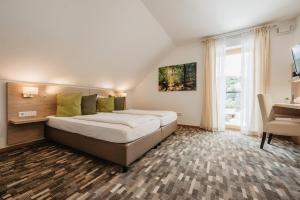 ein Schlafzimmer mit einem Bett mit grünen Kissen und einem Schreibtisch in der Unterkunft Gästehaus Lodermeier in Bad Abbach