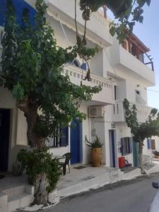 a building with blue doors and a tree in front of it at Angelos Rooms in Myrtos