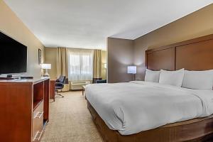 a hotel room with a large bed and a flat screen tv at Comfort Inn & Suites McComb in McComb