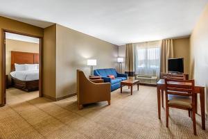 a hotel room with a bed and a blue chair at Comfort Inn & Suites McComb in McComb