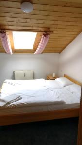 a bedroom with a large white bed with a window at Feriendorf Hauzenberg-Pool&Sauna in Hauzenberg