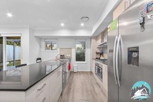 a kitchen with a stainless steel refrigerator and wooden floors at Spacious 4BR Yard Retreat in Kellyville