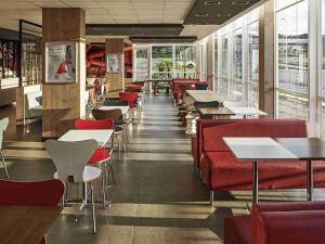 a restaurant with red chairs and tables and windows at ibis Londrina Shopping in Londrina